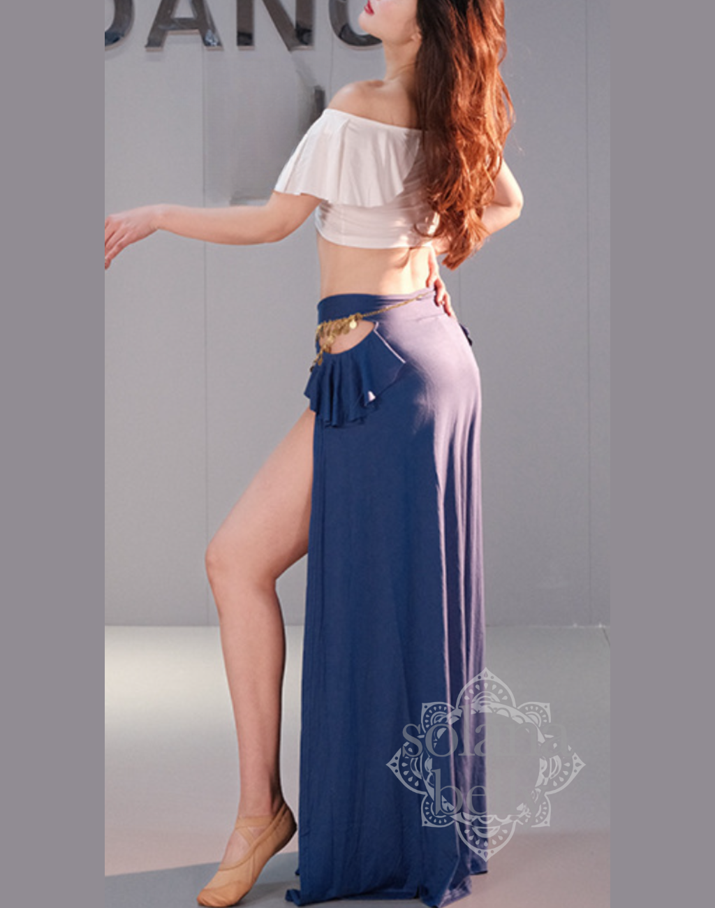 ベリーダンス レッスン着 衣装のホワイト×ブルーのセットアップを着用した女性。肩まわりを美しく見せる白トップスと、脚長効果のあるブルースカートの組み合わせ。初心者向けの安心デザイン。