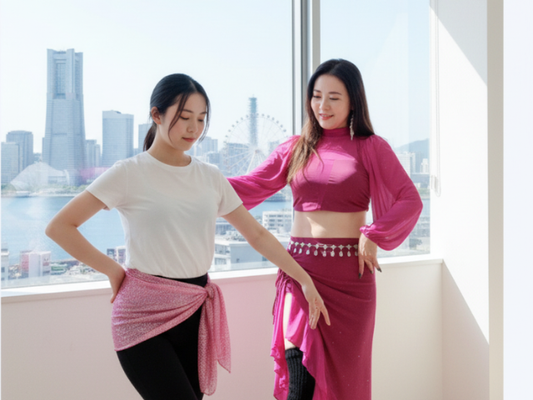 横浜の街並みを背景に、ベリーダンス教室のレッスン着を着た女性がポーズを取っている様子。初心者でも安心して通える雰囲気を表現。