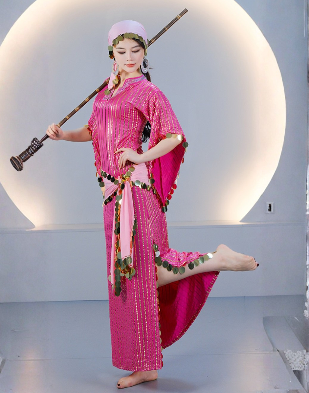 両腕を広げ、ピンクのサイディドレスのフレアスリーブと全身シルエットを見せるベリーダンス衣装を着たベリーダンサー