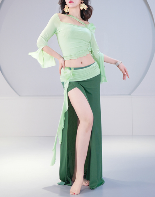 深みのあるグリーンのレッスン着を着た女性が、ベリーダンスの基本姿勢で立つ様子。衣装としても使える上品なデザインが印象的。