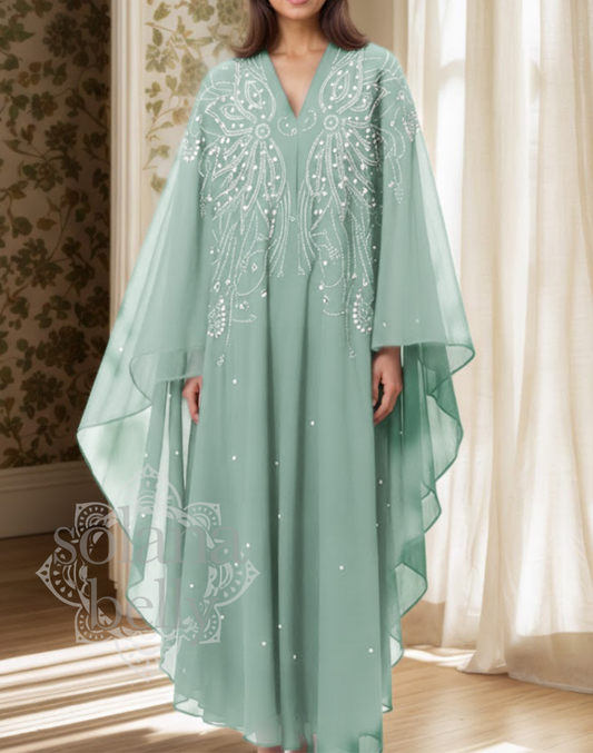 淡いミントグリーンのガラベーヤ（アバヤ）を、ベリーダンス衣装の上に羽織り、フード付きデザインと袖の広がりが分かる立ち姿の着用イメージ。