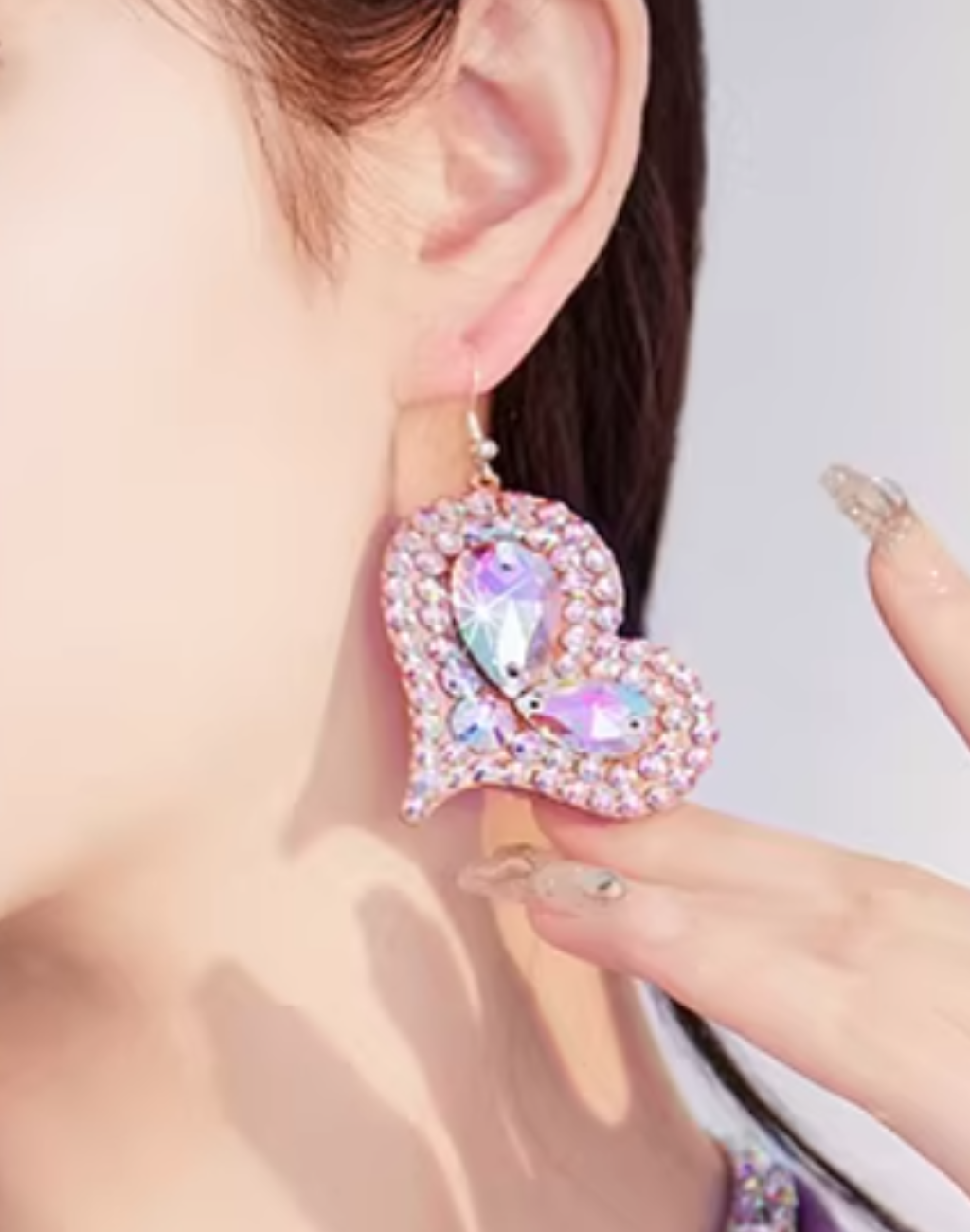 耳元に着用したハート型のベリーダンスアクセサリーのピアスとイヤリング。衣装やレッスン着に合わせた際のサイズ感と輝きが分かるアップ構図。