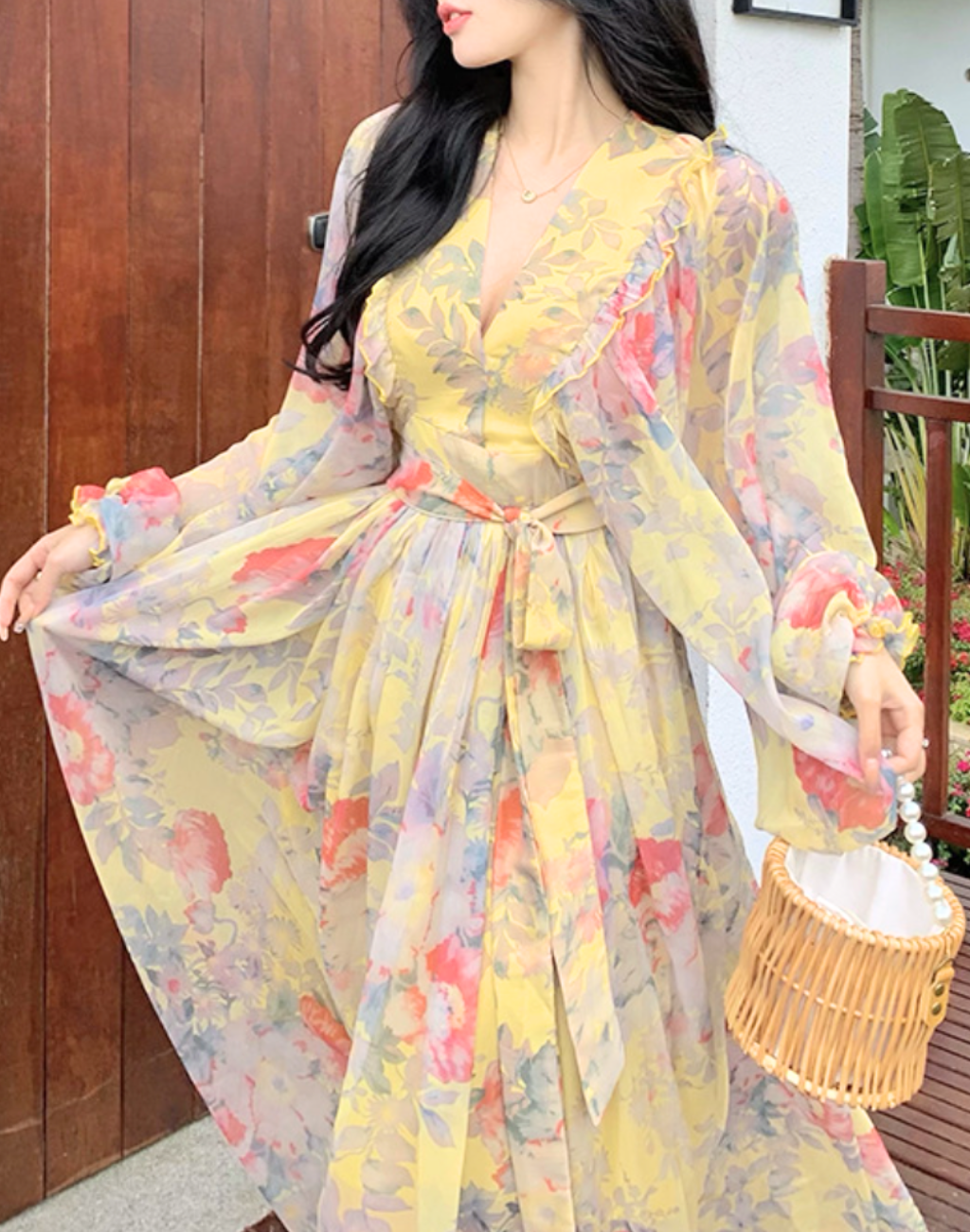 イエローの花柄が広がるガラベーヤワンピースを、ベリーダンス衣装とレッスン着の上から羽織り、庭先で全身シルエットが分かる立ち姿を写したコーディネート写真。