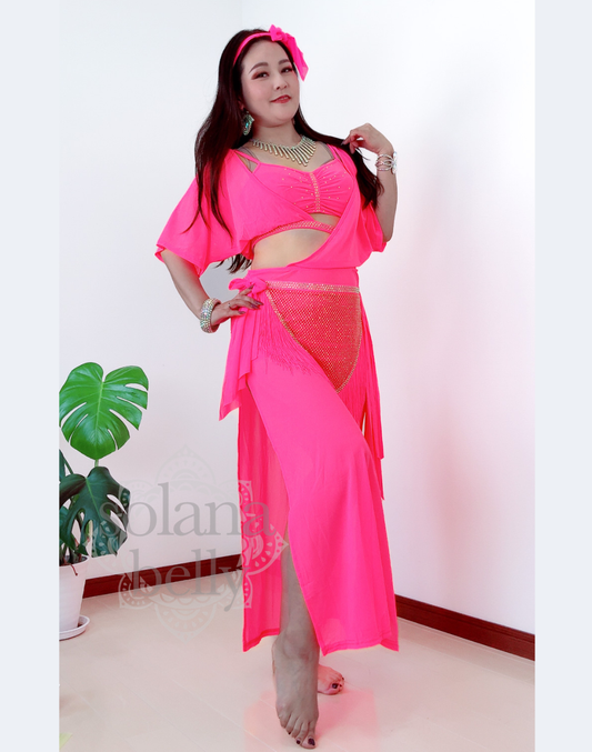 鮮やかなピンクのベリーダンス衣装を着用したモデルが立ち姿でポーズを取るバラディ・シャービースタイル。フリンジ付きヒップスカーフが揺れ、初心者にも挑戦しやすい可愛い印象のデザイン。