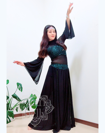 黒のトップスとスカートが一体となったデザインを着用するベリーダンス レッスン着 衣装、袖口が広がりガラベーヤワンピース風に見えるスタイル