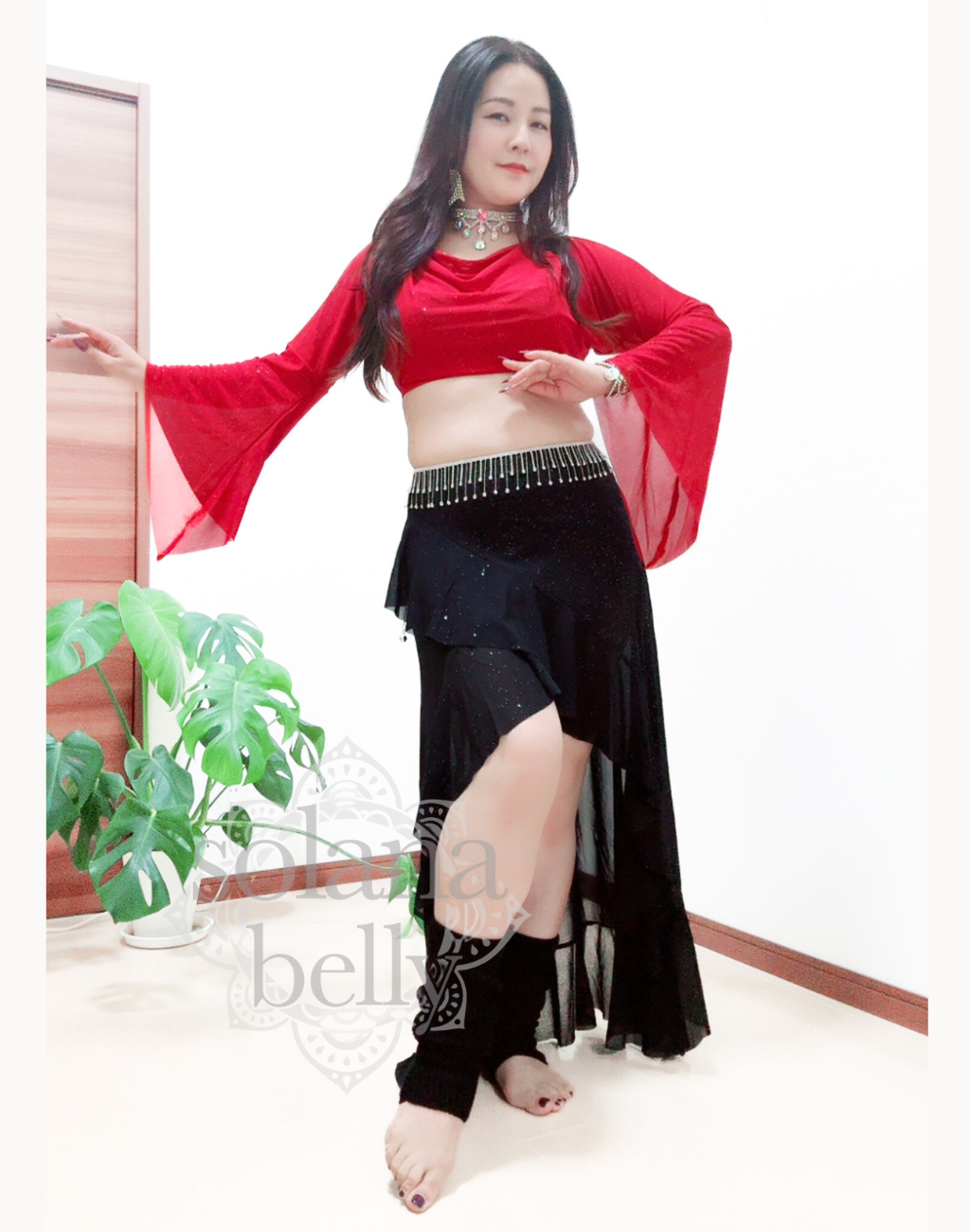 ベリーダンス衣装としても使えるレッスン着を着用しポーズをとっているベリーダンサーの画像。初心者向けの肌見せ控えめデザインになっている。