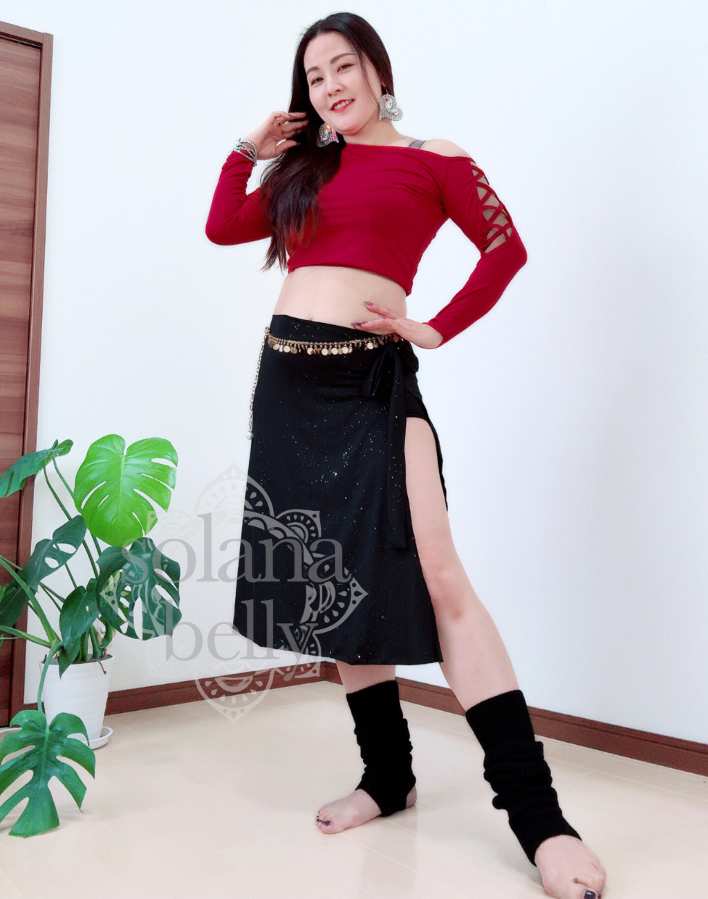 片脚に重心を置いたポーズで動きの途中を捉えた、ベリーダンスのレッスン着。衣装としても着用でき、腰まわりの動作が伝わる構図。