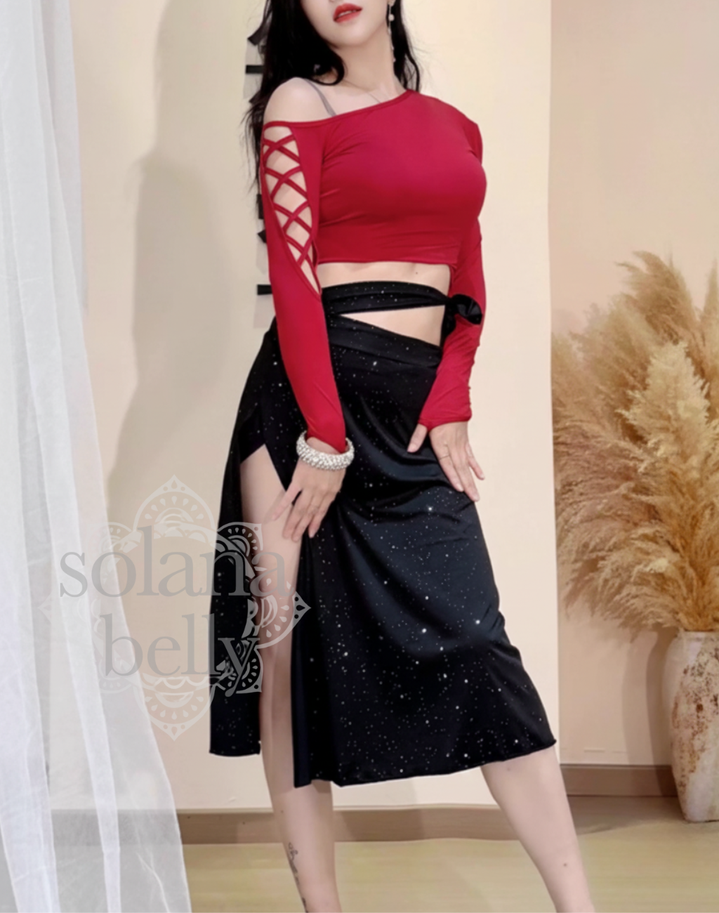 腕を下ろした自然な立ち姿を横から写した、ベリーダンス衣装にも対応するレッスン着。トップスの袖デザインとウエストラインが分かる構図。