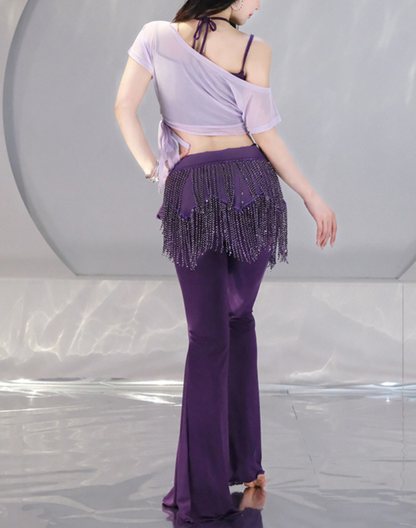 深いパープルのヒップスカーフを腰に巻き、斜め向きに立つ女性モデル。ベリーダンス衣装にも取り入れられるパンツタイプのレッスン着。