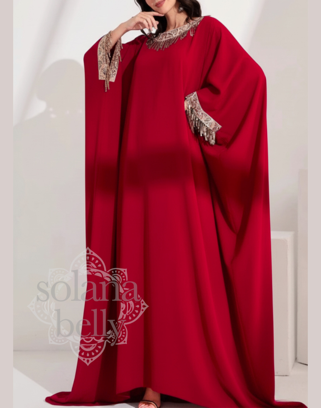 ベリーダンス衣装の上に羽織れるレッドのガラベーヤアバヤを正面から着用し、ゆったりとしたシルエットがレッスン着やステージ前後の動きを上品に包む様子。