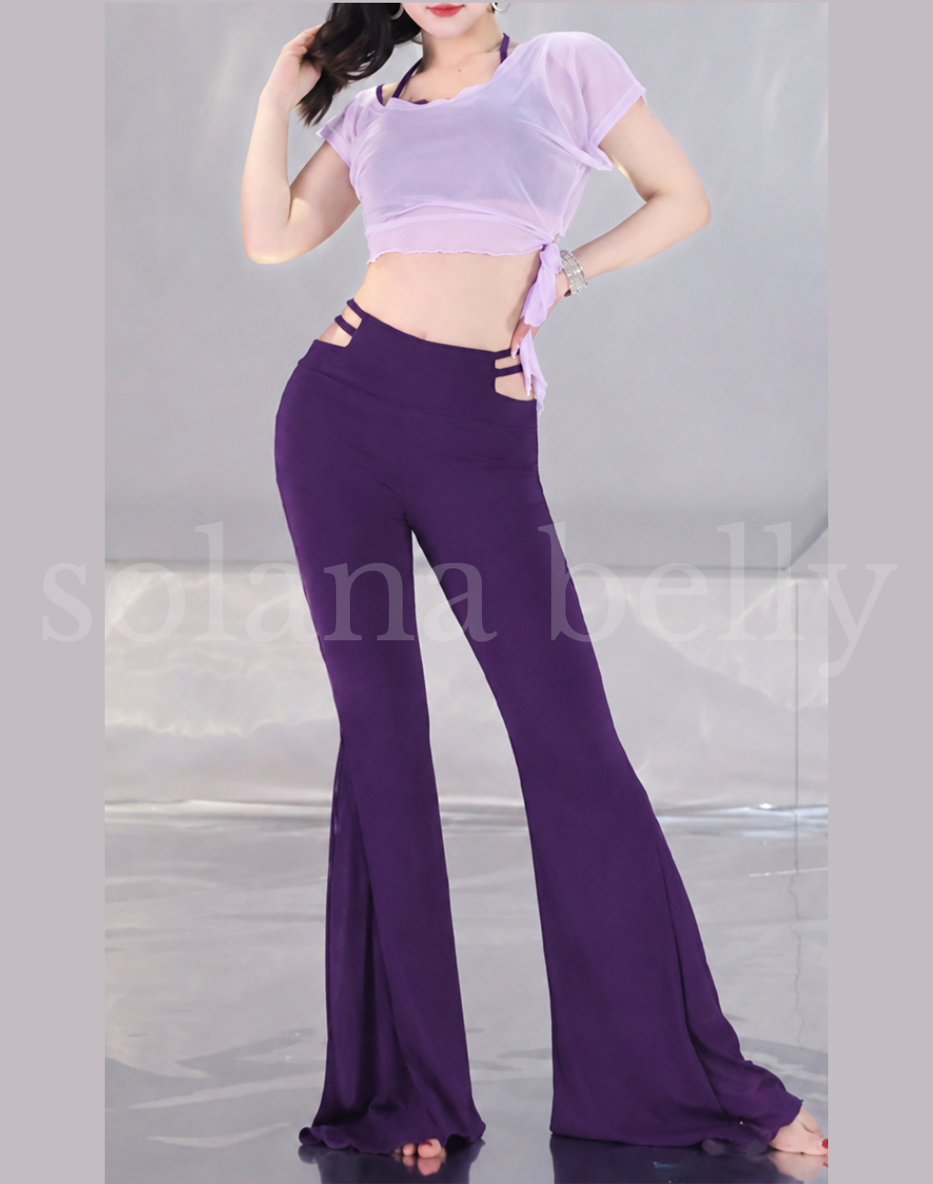 ヒップスカーフを外し、淡いラベンダーのトップスとハイウエストのパープルパンツを着用した女性モデル。ベリーダンス衣装にも使えるレッスン着。
