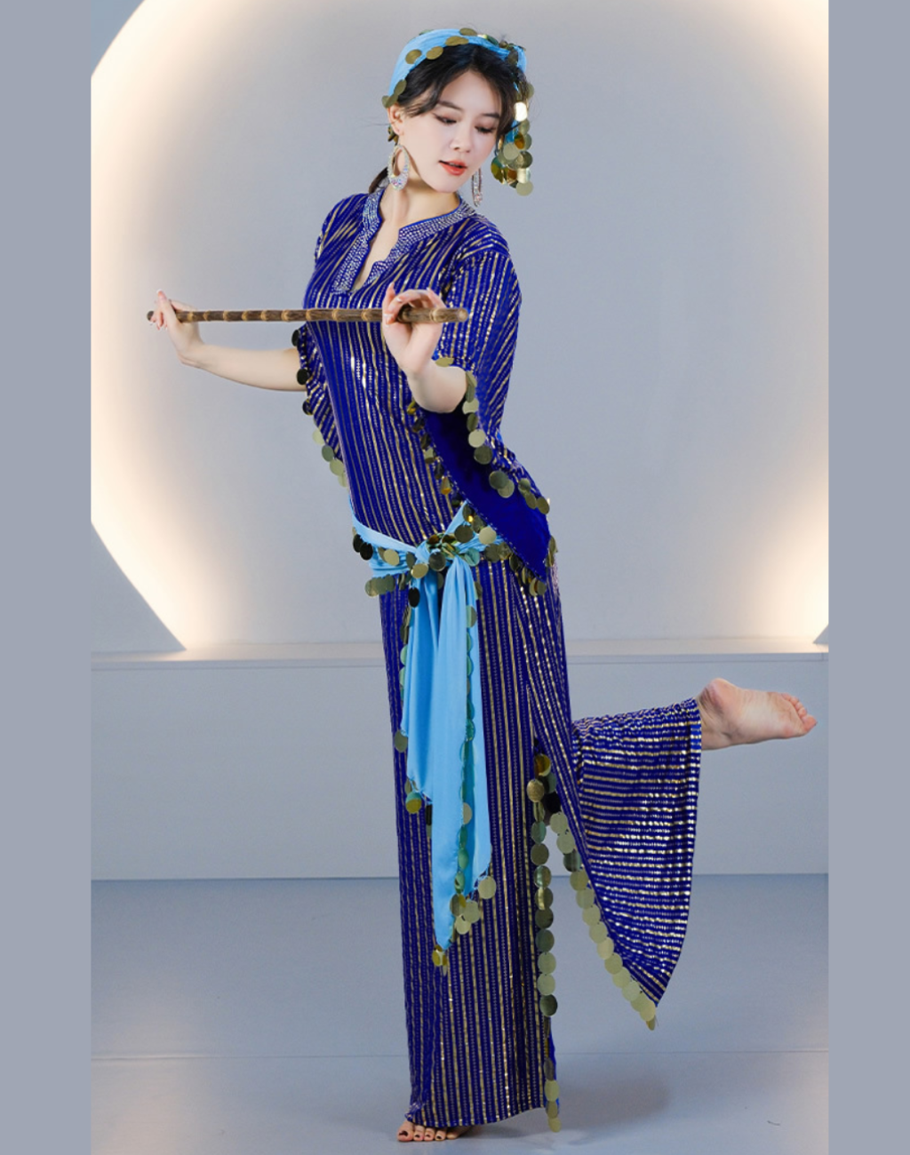 片脚を上げて踊るベリーダンサーが着用したブルーのバラディドレス。ヒップスカーフの揺れが見えるベリーダンス衣装