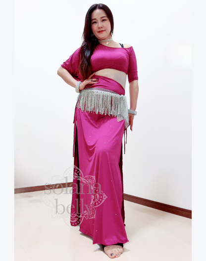 ピンクのベリーダンス レッスン着を着た女性が腕を広げて立つ姿。衣装の滑らかなドレープが上品に流れ、レッスン中の動きを美しく見せる。