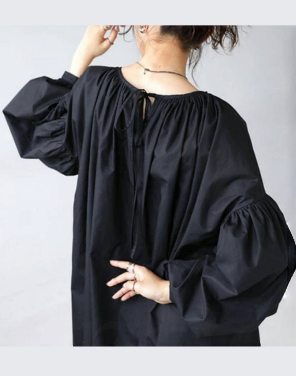 ガラベーヤワンピース（ブラック）の後ろ姿をアップで撮影。背中のリボンとギャザーが分かり、ベリーダンス衣装やレッスン着の上からでも着替えやすい襟ぐりの広さと、ボリューム袖の立体感が見える構図。