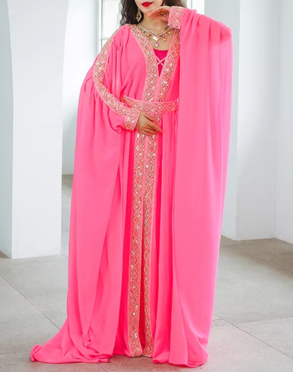 腕を下ろした立ち姿で撮影されたピンクのベリーダンス衣装 ハリージドレス。胸元から縦に入る装飾ラインとシルエットを確認できる正面写真。